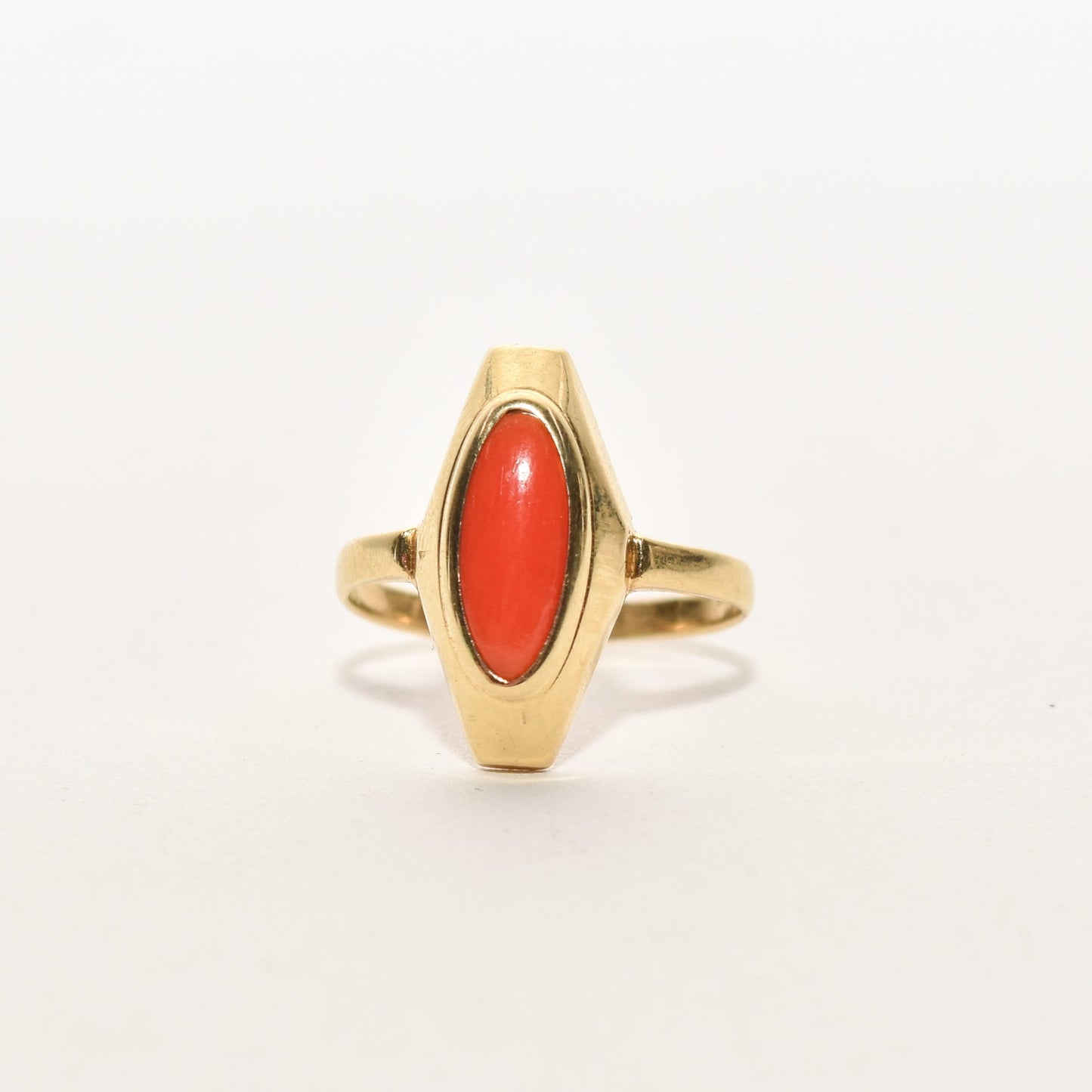 Estate 18K yellow gold ring featuring a marquise-cut red coral, size 5.25 US, displayed on a white background.